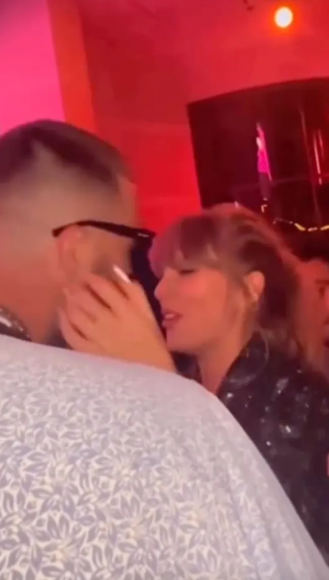 Taylor Swift con sus manos en la cara de Travis Kelce.