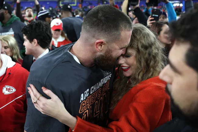 Taylor Swift y Travis Kelce abrazados en un campo de fútbol después de un partido.
