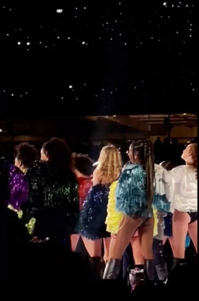 Parte trasera de Taylor Swift actuando rodeada de bailarines de respaldo.