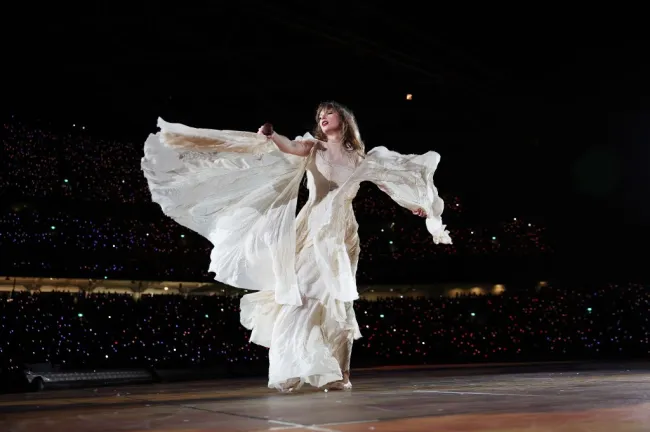 Taylor Swift cantando con un etéreo vestido blanco.