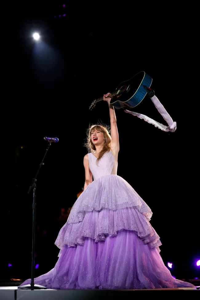 Taylor Swift en el escenario con un vestido morado.