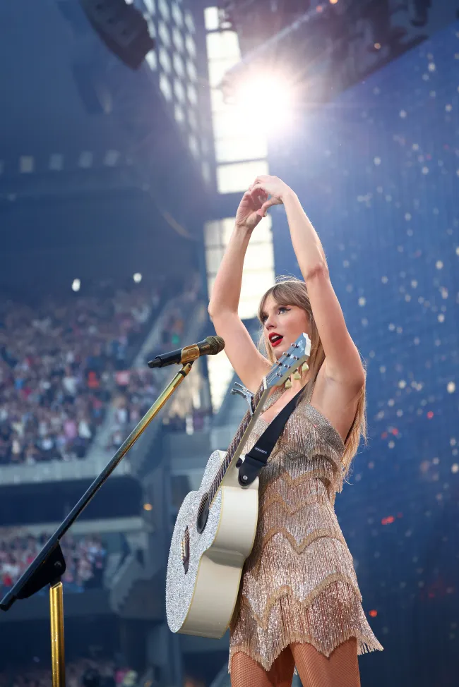 Taylor Swift haciendo forma de corazón con sus manos mientras está en el escenario.