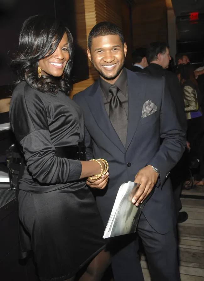 Usher y Tameka sonriendo vestidos todos de negro.