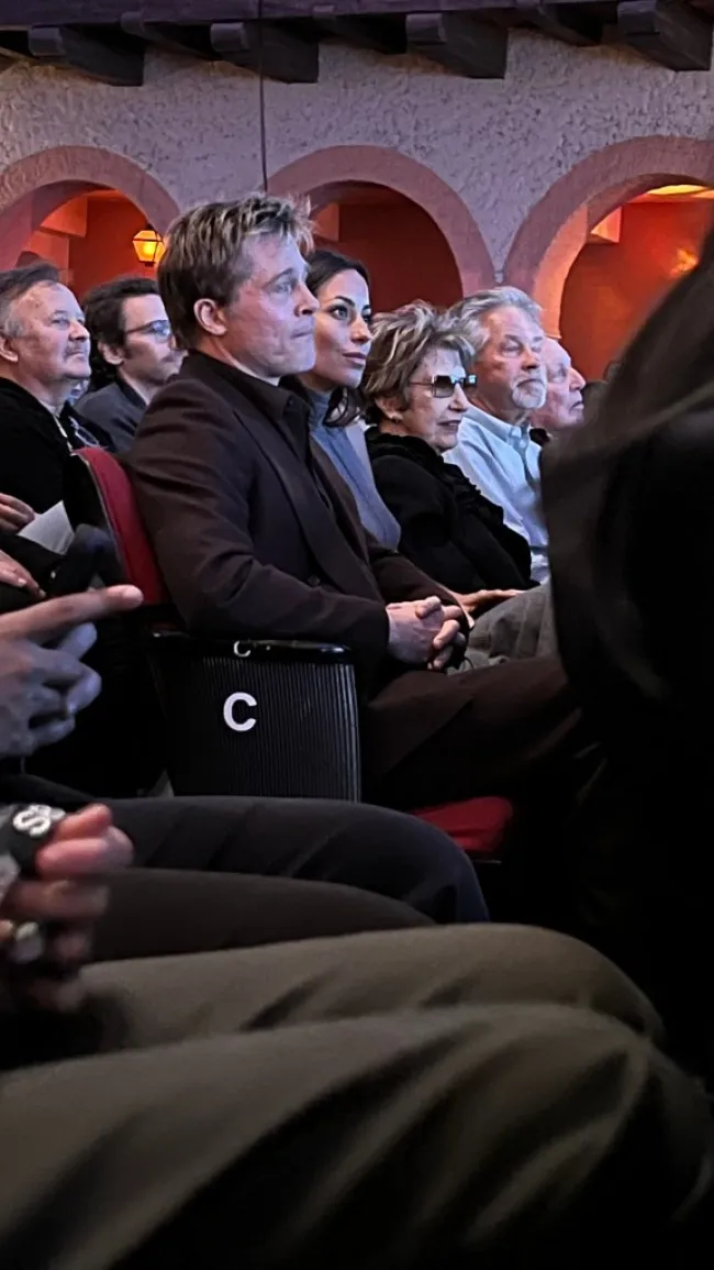 Brad Pitt e Inés de Ramon sentados uno al lado del otro en una sala de cine.