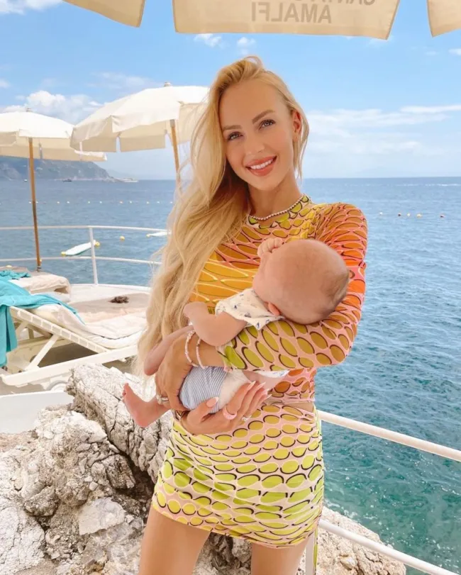 Christine Quinn sosteniendo a su bebé con el océano de fondo