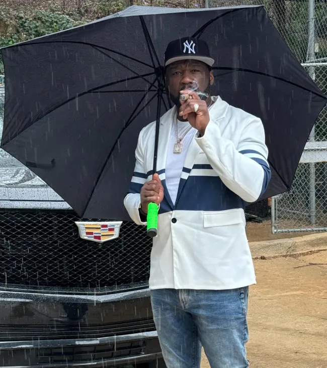 50 Cent fumando un cigarro bajo un paraguas