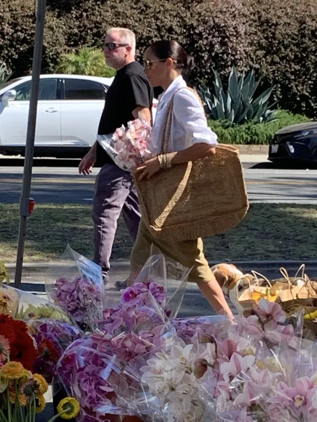 Meghan Markle sostiene flores mientras compra.