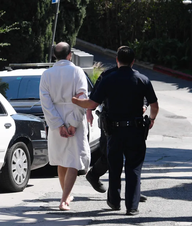 Christian Richard siendo arrestado con una bata blanca.
