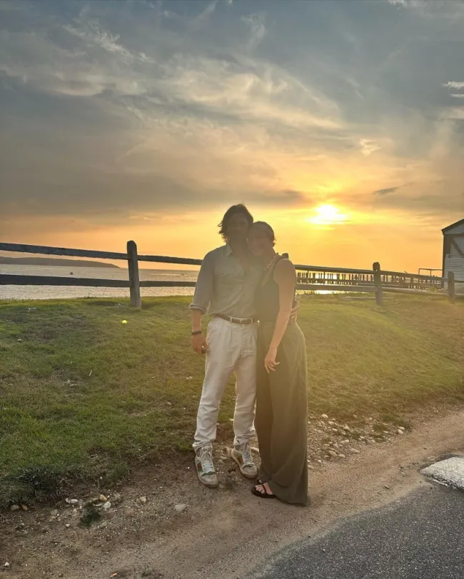 Gwyneth Paltrow y Brad Falchuk de pie frente a una puesta de sol.