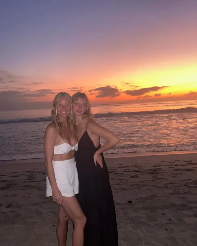 Gwyneth Paltrow y su hija Apple sonriendo en una playa al atardecer