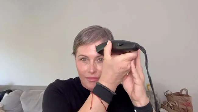 Nicole Eggert con una maquinilla de afeitar eléctrica en la cabeza