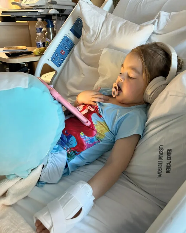 La hija de Gunnar Peterson mirando una pantalla en una cama de hospital.