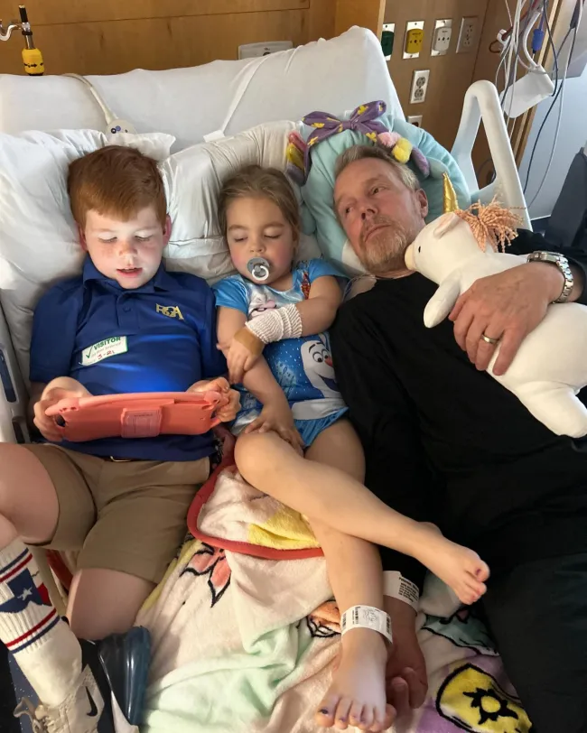 gunnar peterson acostado en una cama de hospital con su hijo y su hija