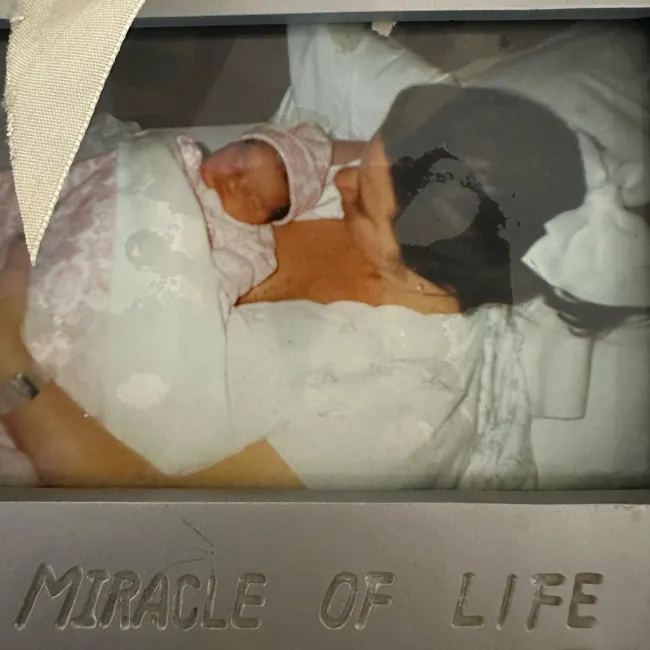 Fotografía enmarcada de Karen Houghton acostada en la cama sosteniendo a su recién nacido