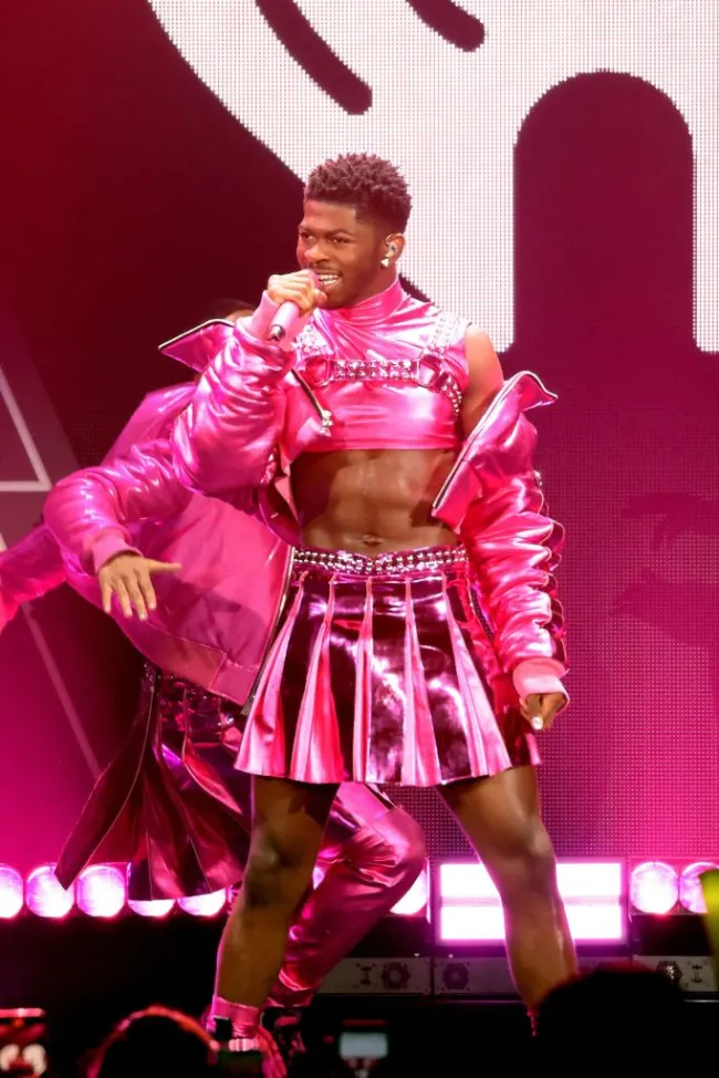 Lil nas x actuando en el escenario con un traje rosa intenso