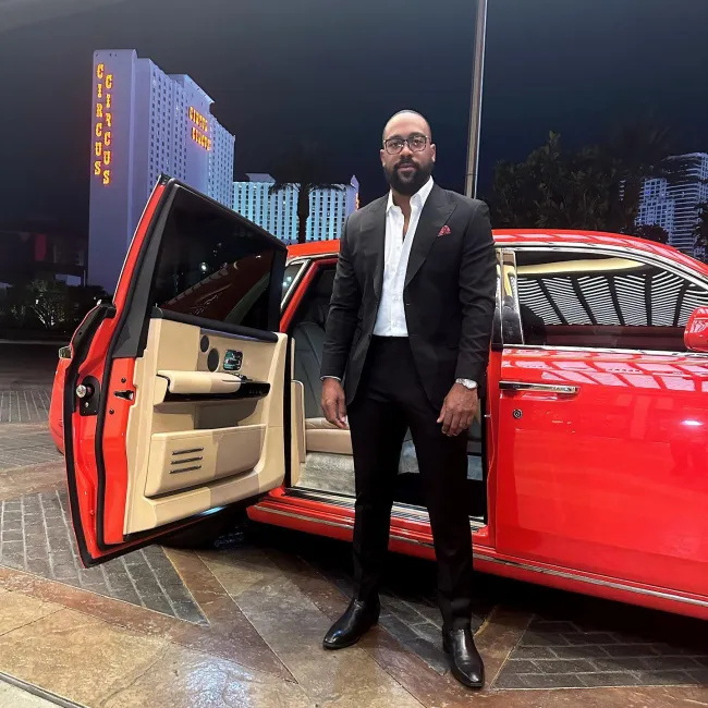 marcus jordan parado frente a un auto deportivo rojo