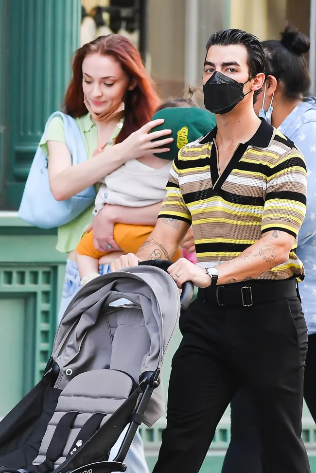 Sophie Turner sosteniendo a su bebé junto a Joe Jonas empujando un cochecito