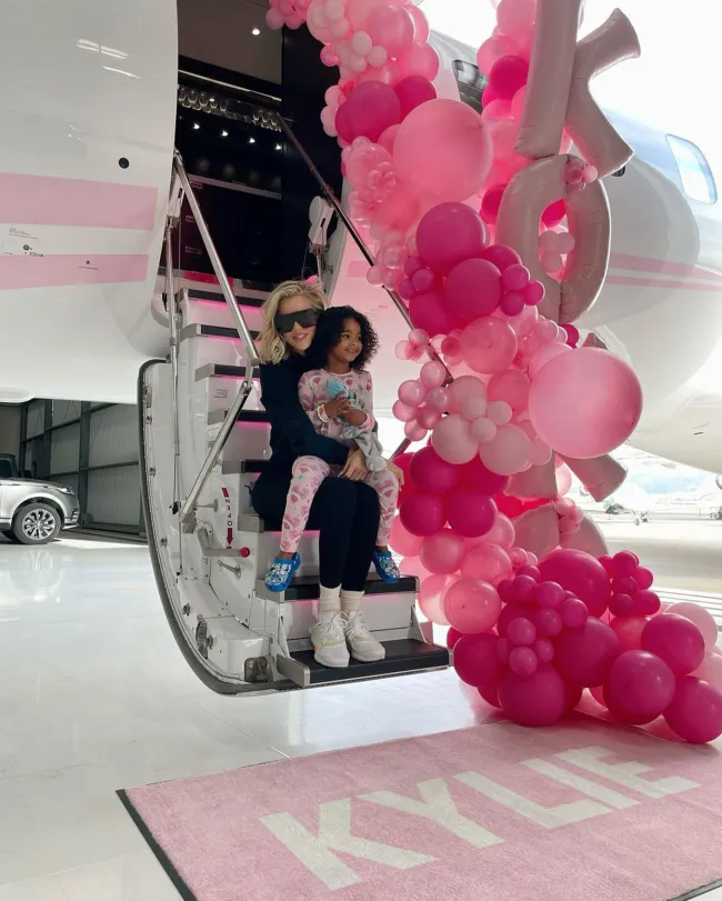 Khloé Kardashian y su hija True Thompson sentadas en las escaleras de un avión