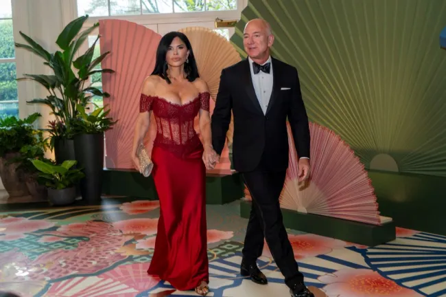 Lauren Sánchez, con un vestido rojo, toma de la mano a Jeff Bezos.