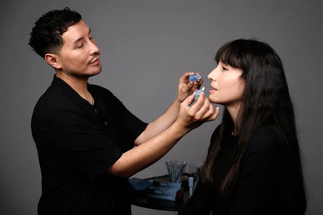 Un maquillador aplicando un aceite para labios.