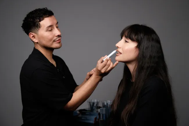 Un maquillador aplicando un lápiz labial