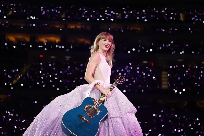 Taylor Swift en el escenario con una guitarra azul.