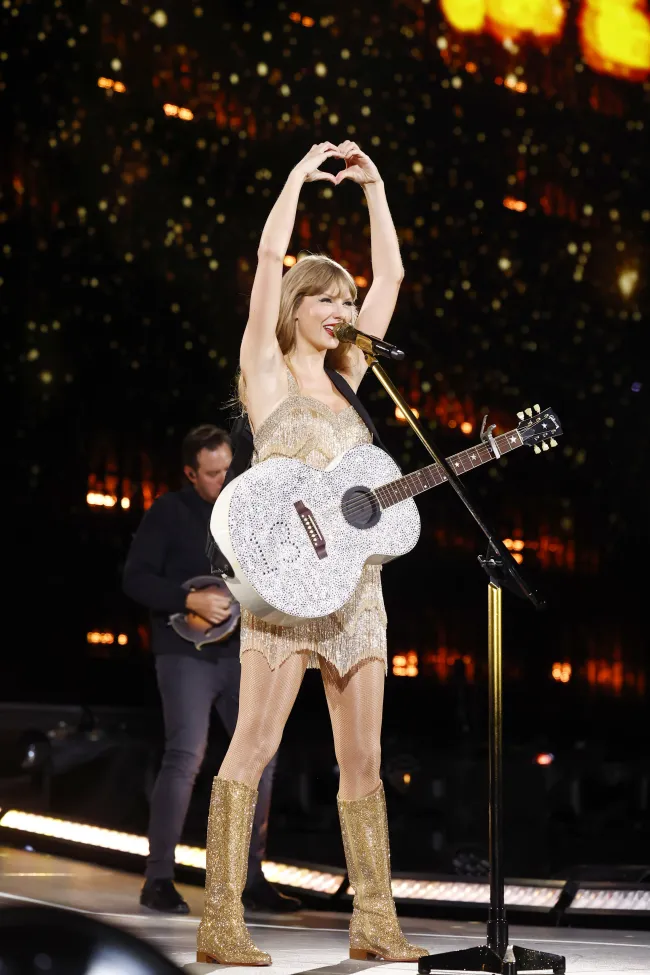 Taylor Swift en el escenario haciendo un corazón con sus manos.