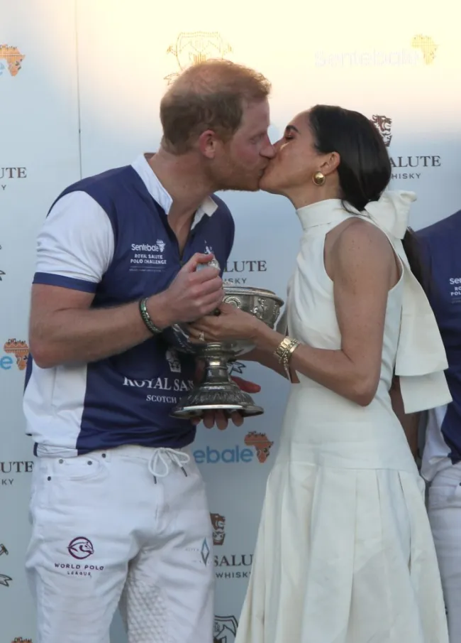 Meghan Markle le da un beso al Príncipe Harry mientras le entrega un trofeo de polo.
