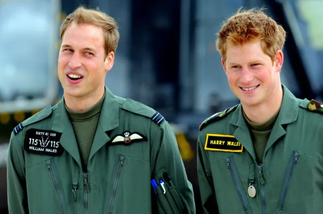 El príncipe William y el príncipe Harry comparten una broma juntos, vestidos con monos de vuelo.