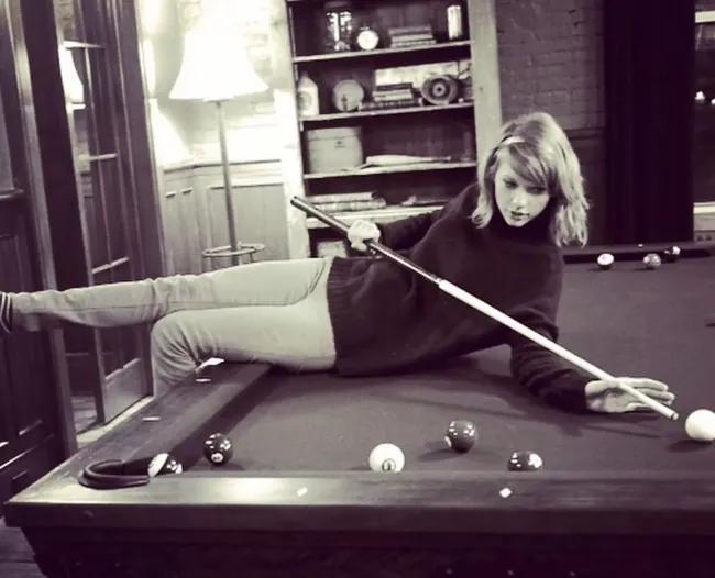 Taylor Swift sentada en una mesa de billar