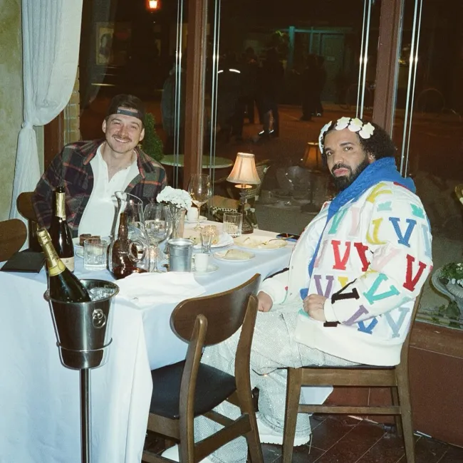 Morgan Wallen y Drake sentados en la mesa de un restaurante.
