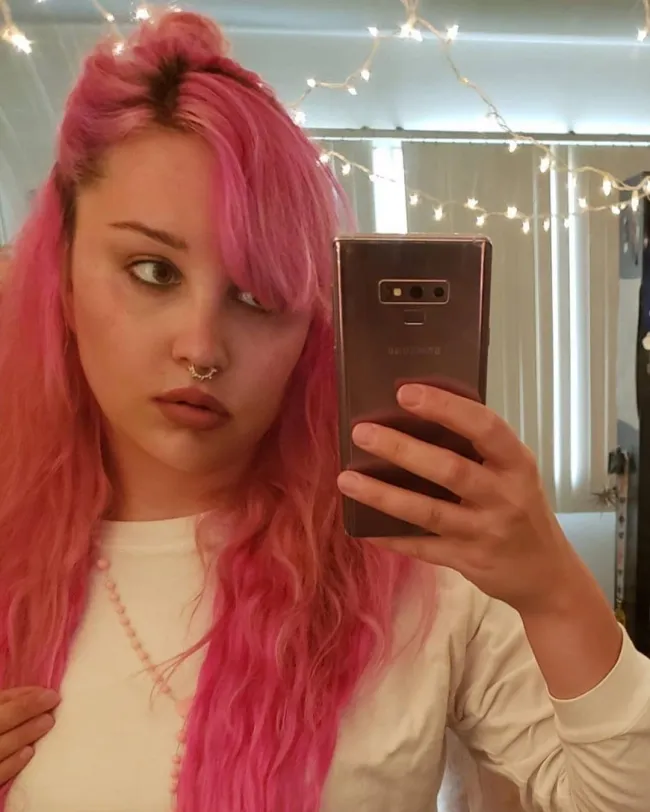 Una selfie en el espejo de Amanda Bynes con cabello rosado.
