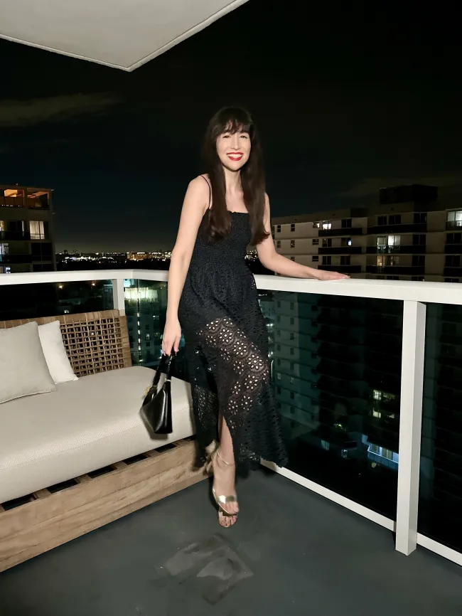 La autora con un vestido negro en el balcón de un hotel