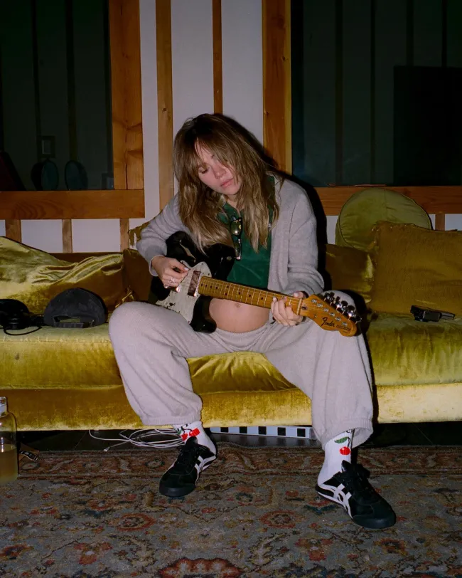 Suki Waterhouse muestra su panza mientras toca la guitarra.