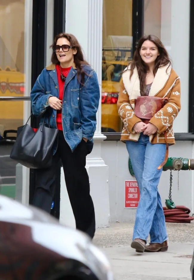Suri Cruise sonríe mientras camina con su madre Katie Holmes.