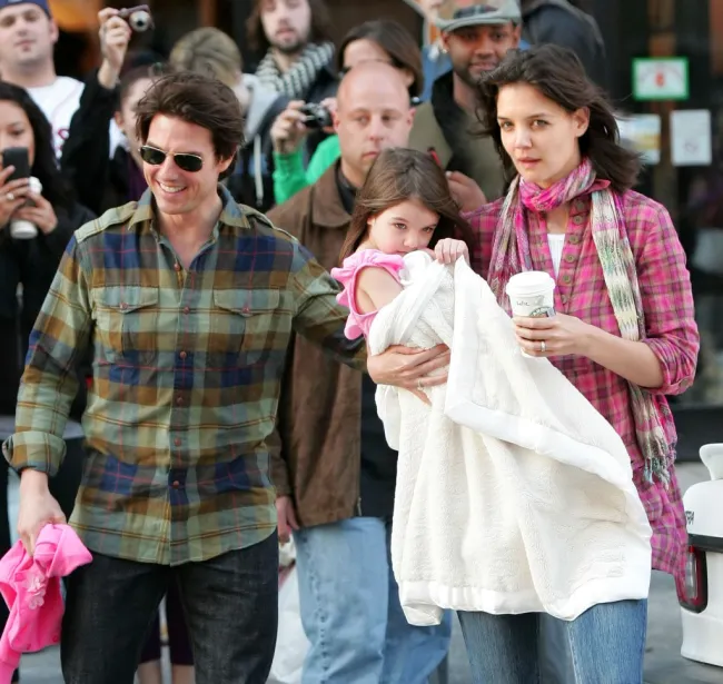 Katie Holmes carga a Suri Cruise mientras Tom Cruise camina junto a ellos.