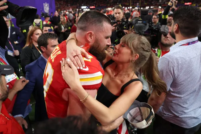 Travis Kelce y Taylor Swift abrazándose en un campo de fútbol después de un partido.