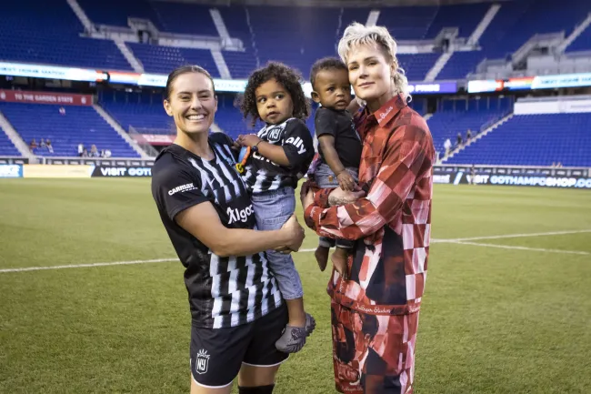 Ali Kreiger y Ashlyn Harris con sus dos hijos en el campo de fútbol.