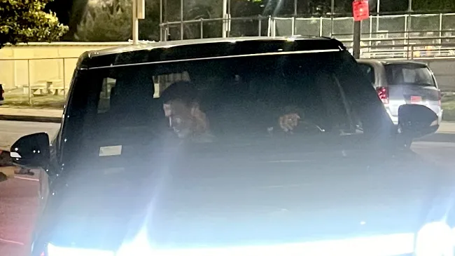 Ben Affleck en un auto inclinándose para abrir la puerta principal.
