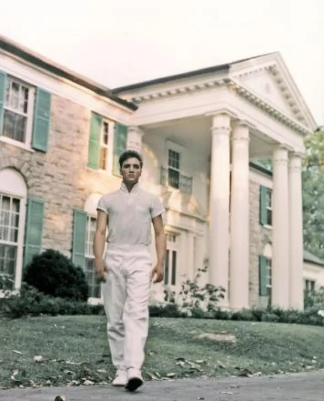 Elvis Presley parado frente a Graceland.