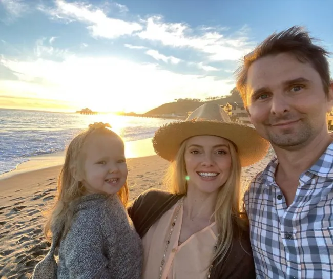 Matt Bellamy, Elle Evans y su hija Lovella en la playa.