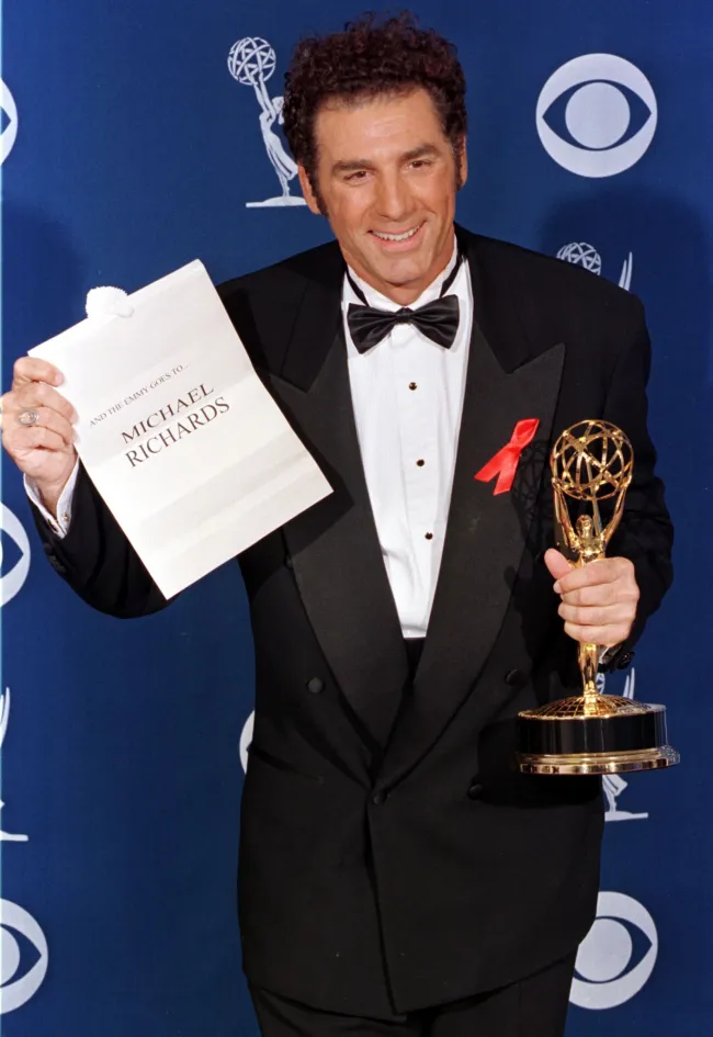 Michael Richards sosteniendo un Emmy y un sobre que revela su nombre como ganador